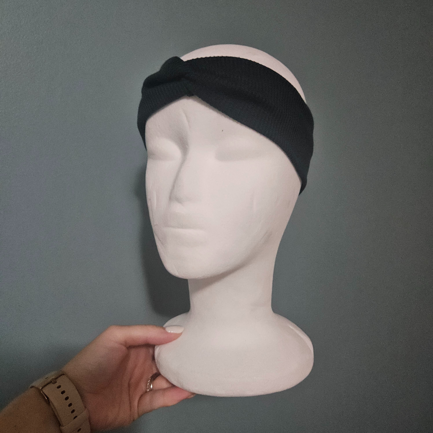 Dark green headband on a mannequin head against a gray background