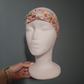 Floral headband on a mannequin head against a gray background